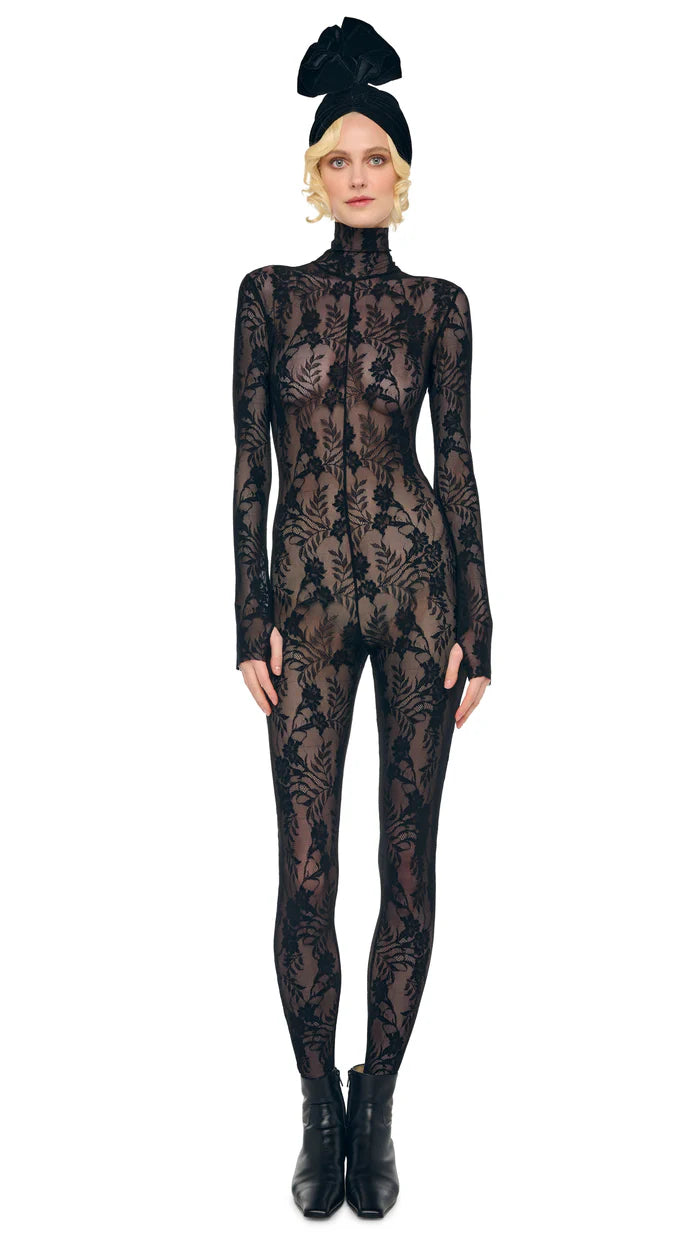 Model wearing Norma Kamali black lace slim-fit catsuit with turtleneck, long sleeves, and stirrup feet