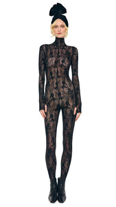 Model wearing Norma Kamali black lace slim-fit catsuit with turtleneck, long sleeves, and stirrup feet
