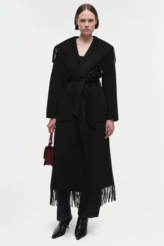 Model wearing Simkhai Carrie Fringe Coat in black with shawl collar and self-tie belt