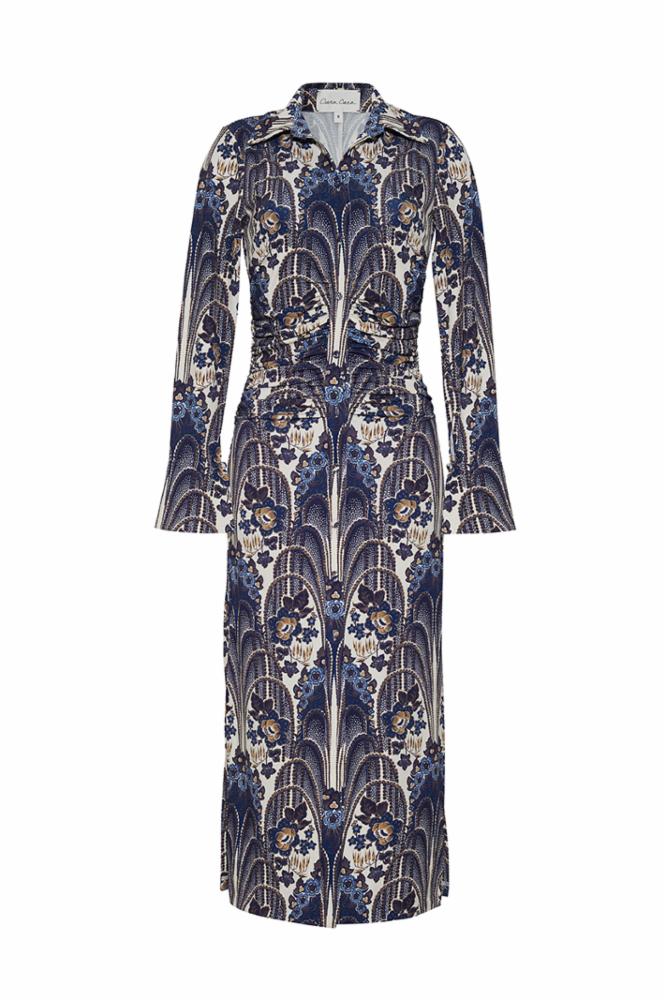 A fitted slinky jersey midi dress with decorative ruching at the waist, fluted sleeve cuffs with bungee elastic and buttons, and a functional center front placket with baby snaps. Features a unique placed print and side seams running from front to back.