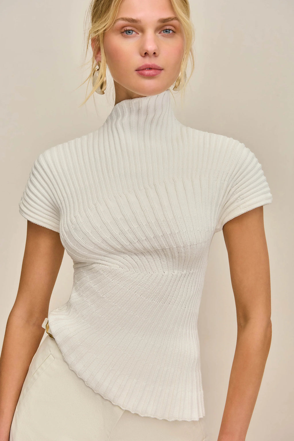 Cult Gaia Annemie Top — asymmetrical knit top with a mock neck, flared cap sleeves, and radial stitch detailing, featuring an uneven hem and a slightly relaxed fit.