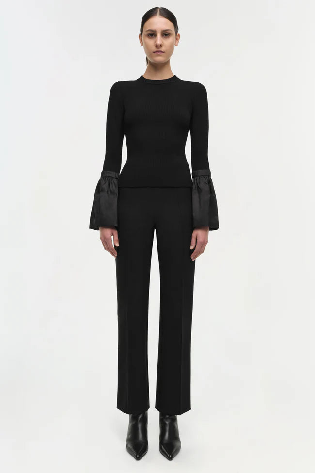 Model wearing Simkhai Agata Top in black with long sleeves and dramatic flared cuffs