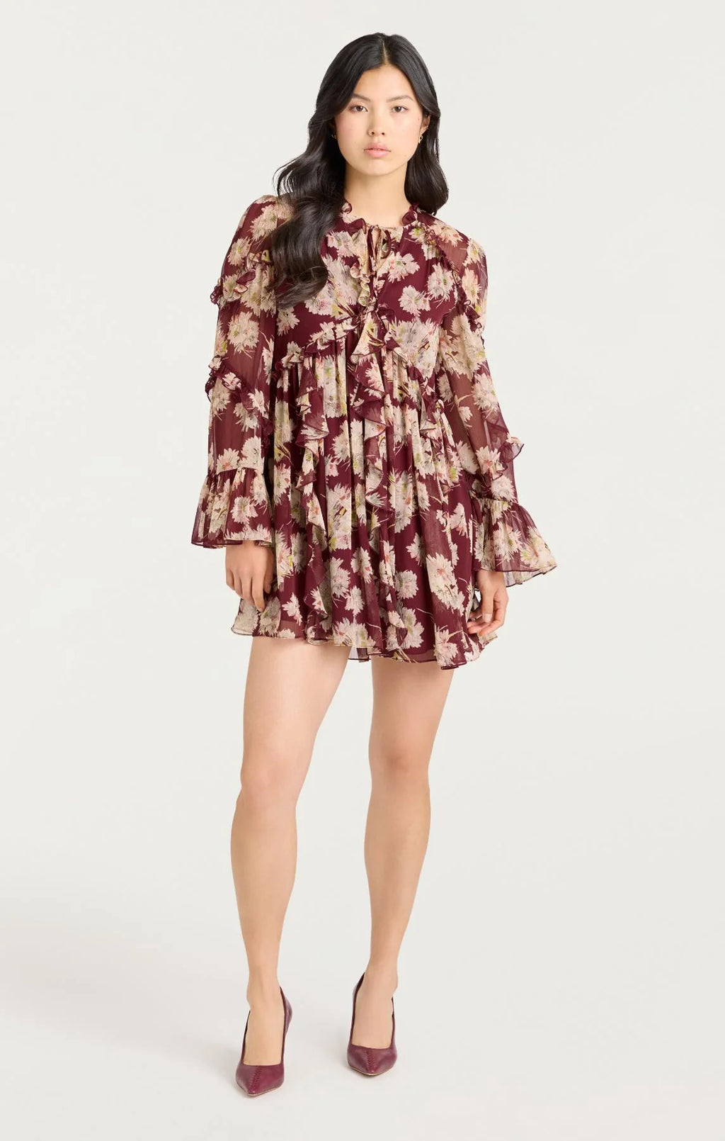 Woman wearing Cinq à Sept Mae Bouquet Albani Dress, a long-sleeve chiffon mini dress with ruffle tiers, flared cuffs, and tie-neck detail; elegant fall outfi