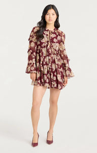 Woman wearing Cinq à Sept Mae Bouquet Albani Dress, a long-sleeve chiffon mini dress with ruffle tiers, flared cuffs, and tie-neck detail; elegant fall outfi